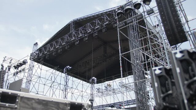 Installation of a huge stage for an outdoor concert. Large stage under construction. Metal structures for concert venues. Installation of light and sound devices on stage for a concert.