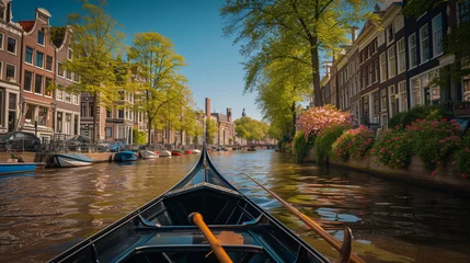 Fotobehang A gondola ride through the canals of Amsterdam Netherlands with historic houses and blooming tulips lining the waterways. © Lucas