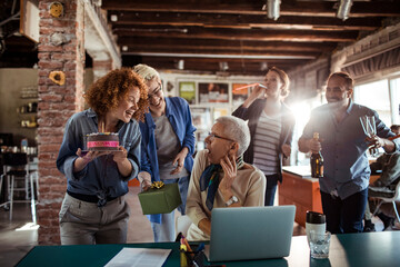 Multigenerational and diverse group of people celebrating a birthday in a startup company office