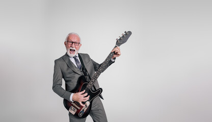 Old male entrepreneur screaming and playing electric guitar while performing on white background