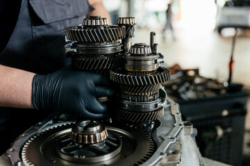 a disassembled gearbox in the hands of an experienced car mechanic who repairs broken mechanisms and parts in a car