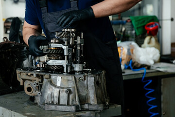 a disassembled gearbox in the hands of an experienced car mechanic who repairs broken mechanisms...