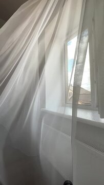 Wind ruffles tulle on open window