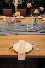 Luxury fantastic table setting decor for celebration. Details of decorating the holiday with roses and candles in the restaurant.