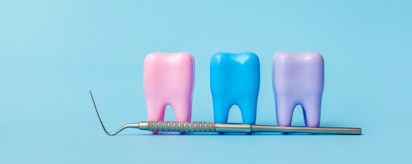 Three multi-colored models of teeth on a blue background. Dental probe. Dental health concept. Flat lay, copy space for text. Dentistry. Place for text. Oral health and dental examination. Dentistry