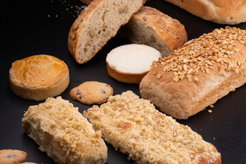 various breads and shaped cakes with sesame and chestnuts on a black table at a bakery