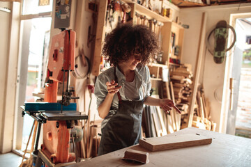 Young woman working with wood in carpentry garage