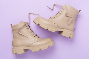 Beige trendy boots on color background, top view.