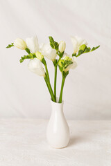 Nice bouquet of white freesia flowers in vase on table