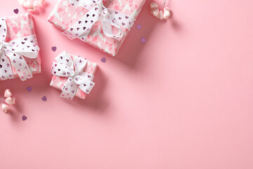 Valentine's Day background with pink gift boxes, hearts, confetti. Flat lay, top view, copy space.