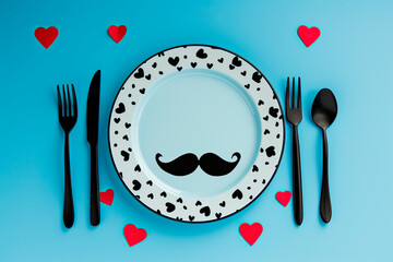 plate, cutlery, knife, fork, black mustache and hearts on blue background. Father day concept