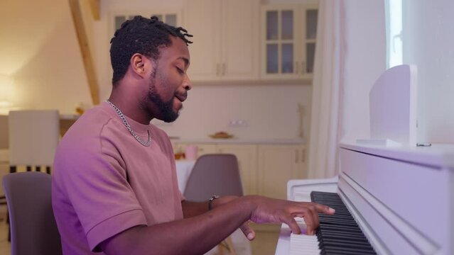 calm weekend at home, young black man playing piano and singing romantic song, portrait