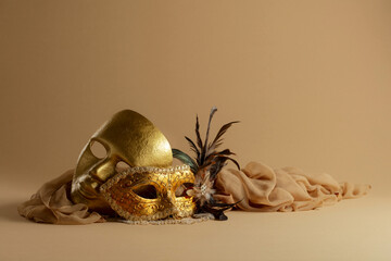 Golden Venetian carnival masks on a beige background.