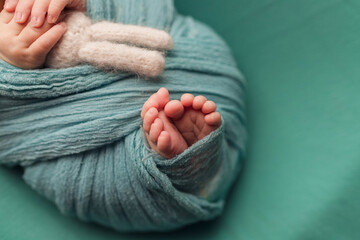 Newborn baby's legs wrapped in turquoise. Turquoise background for a photo shoot.