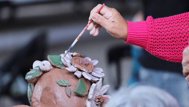 Lady's hands while painting a ceramic art piece. Art classes for older adults. Artist working on crafts. Lady's hands while painting a ceramic art piece. Art classes for older adults. Artist working. - Powered by Adobe