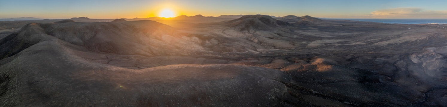 Panoramic sunset view over the volcanic ridges of Fuerteventura's barren landscape, extending from El Cotillo to Majanicho with the Faro del Toston in sight