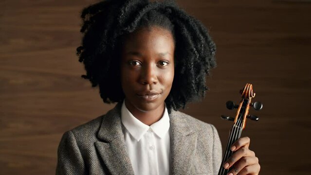 Face, art and violin with black woman performer in studio on wooden wall background for orchestra music. Portrait, instrument and creative young person at concert for performance or entertainment