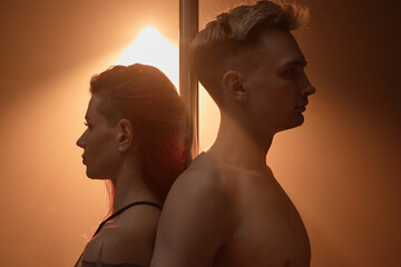 Medium close up with side view of young Caucasian male and female pole dancers standing back to...
