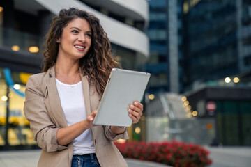 Stylish young businesswoman using digital tablet in downtown financial district in the city.