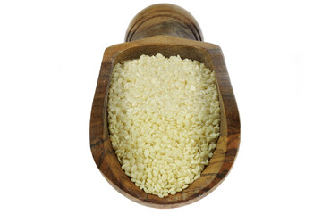 sesame seeds in an olive wood weighing scoop isolated on white background