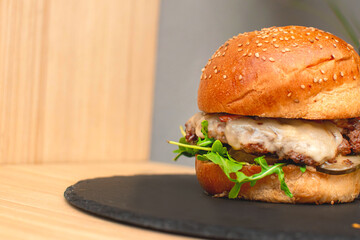 Imagen horizontal de un plano a detalle de una hamburguesa de res con queso y vegetales 