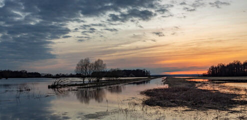 Sunset over a flooded river, rural landscape, spring flood, flooded field after winter
