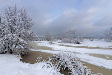 Winter landscape, a river covered with ice and snow, a beautiful sky with clouds against the background of white snow and a frozen river
