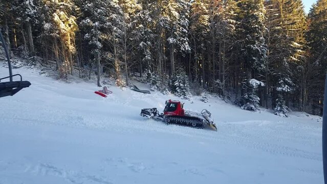Snowplow machine working on the ski resort. Snow groomer preparing the ski slope.