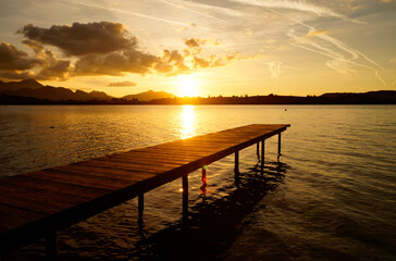 Obraz premium a long pier at Forggensee lake in the Bavarian Alps at romatic sunset on a sunny September evening