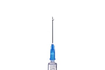 Medical syringe needle with a drop of liquid at the end.