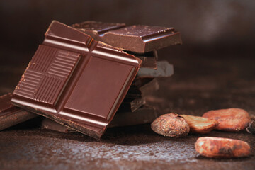 Broken dark chocolate bar and chocolate flakes on black kitchen table