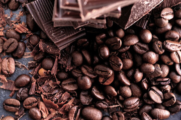 Broken dark chocolate bar and chocolate flakes on black kitchen table