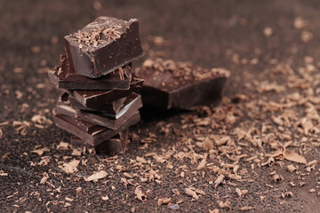 Broken dark chocolate bar and chocolate flakes on black kitchen table