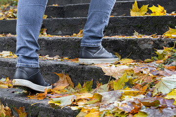 a man climbs the steps of a staircase strewn with yellow leaves.