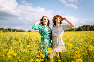Two Beautiful women in the blooming field. Nature, vacation, relax and lifestyle. Summer landscape.