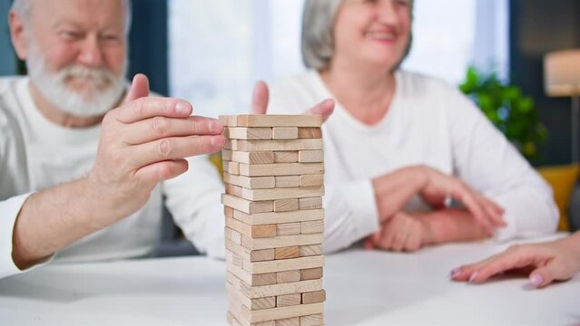 board games, happy male and female pensioners having fun playing jenga sitting at the table at home