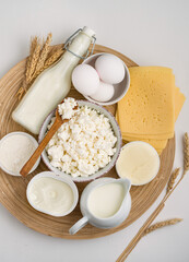 Assortment of dairy products, milk, cottage cheese, cheese, cream cheese, butter, eggs and yogurt on a wooden stand on a light background, top view.