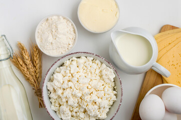Fresh dairy products, milk, cottage cheese, cheese, cream cheese, butter, eggs and yogurt on a light background. Close up, top view.