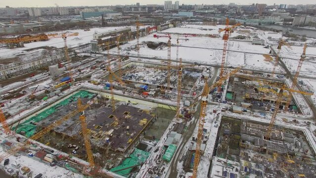 Several cranes work on large building site in city at winter day
