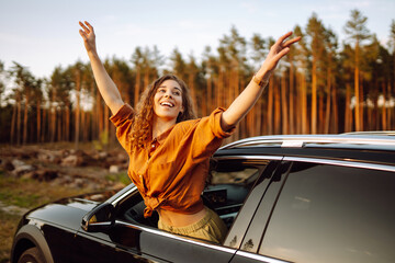 Young  woman leaning out of the car window enjoying nature. Lifestyle, travel, tourism, active life.