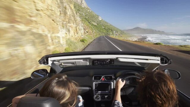 Couple, driving in car and road trip by beach for adventure, holiday vacation and sightseeing on mountains. Back of people or driver in speed, fast convertible or luxury transport for travel journey