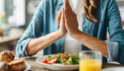 woman's hands clasped in prayer, conveying gratitude and spirituality before a meal