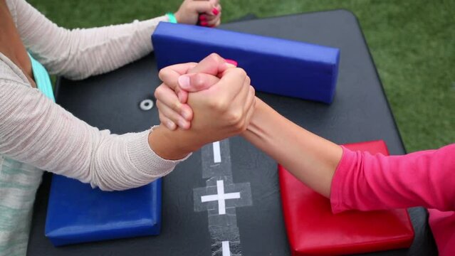 Girl and woman are fighting in arm-wrestling on a table