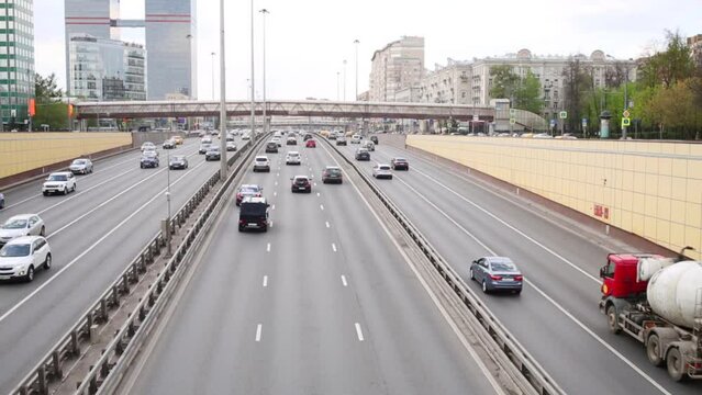 Lot of cars go on modern highway in city at day, text on truck - concrete