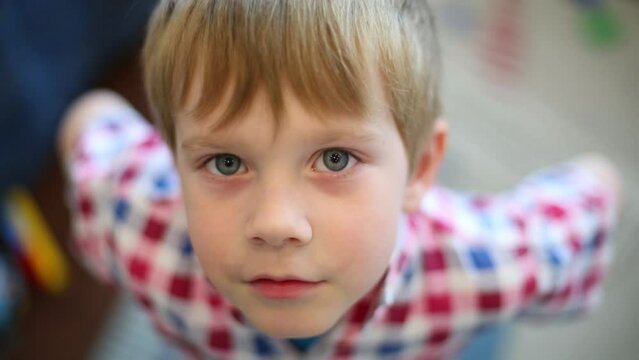 Little boy in shirt looks up and speaks, shallow dof