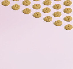 A pattern made of almond cookies geometrically laid out on a pink background. Copy space. Sweets minimal concept.