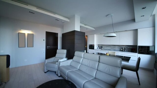 The light is turned off and in an apartment with kitchen and living room