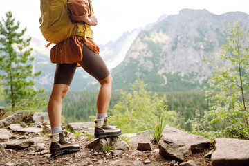 Close-up of female legs in hiking boots on a hiking trail, on top of a mountain outdoors. Travel,...
