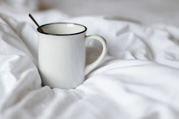 Morning Comfort: A White Mug on a Cozy Bed
