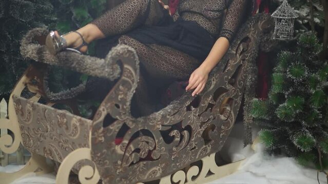 Woman in sexy dress without bra sitting in decorated sled in smoke.